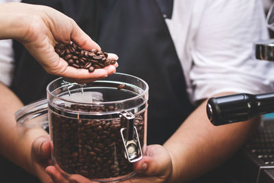 Midsection of barista holding roasted coffee beans