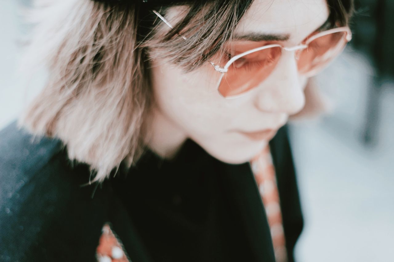 CLOSE-UP PORTRAIT OF YOUNG WOMAN WITH EYEGLASSES ON HAIR