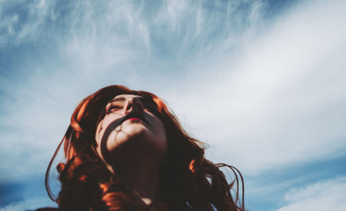 Low angle view of woman looking up against sky