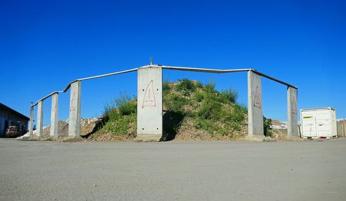 Road by built structure against blue sky