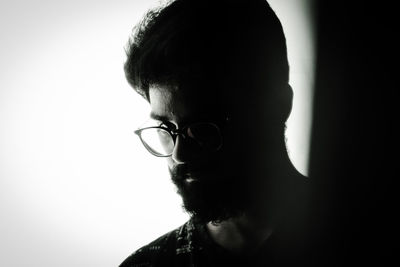 Close-up of young man wearing eyeglasses against white background