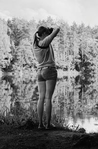 Rear view of woman standing by lake