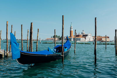 Gondola moored in grand canal by san giorgio maggiore against clear blue sky