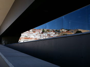 Bridge by buildings against sky seen through window