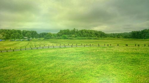 Scenic view of grassy field against cloudy sky