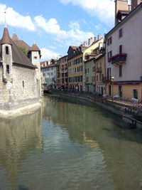 Canal in city against sky