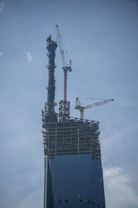 Low angle view of crane at construction site against sky