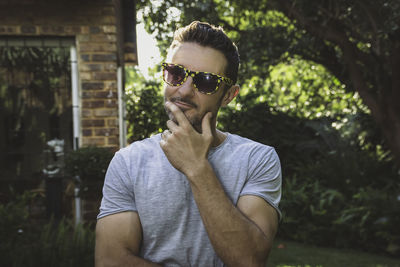 Portrait of young man wearing sunglasses while standing outdoors