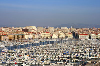 Aerial view of city buildings by sea against clear sky