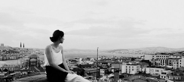 Woman sitting on observation point against residential district