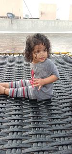 Cute boy sitting on brick wall