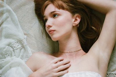 Portrait of young woman lying on bed at home