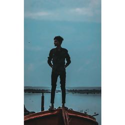 Young man standing in sea against sky