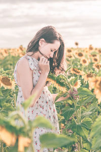 Woman standing by flower on field