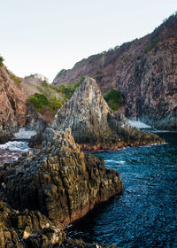 Scenic view of rocks in sea against clear sky