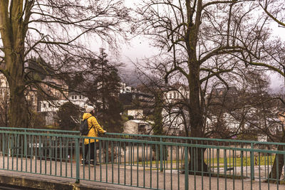 Rear view of tourist sanding by railing against tree