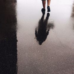 Low section of man walking on puddle during rainy season
