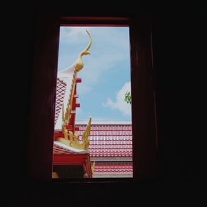 Statue by sea against sky seen through window