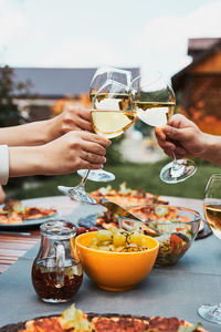 Friends making toast during summer picnic outdoor dinner in a home garden