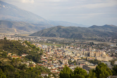 Aerial view of townscape and mountains against sky