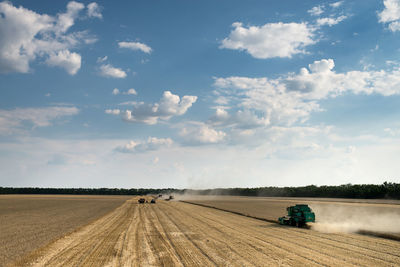 Harvester on wheat field against sky