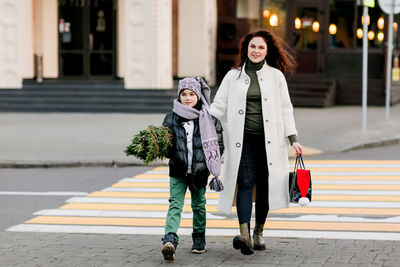 A beautiful mother and her son are walking out of the store, holding a bag of gifts 