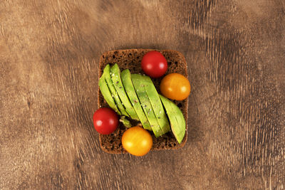 Sandwich or toast on the wooden background. toast with avocado, tomatoes and almond. vegan food.