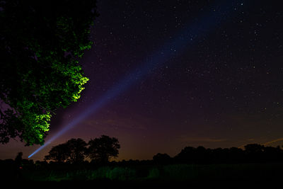 Scenic view of field against sky at night with flashlight beam