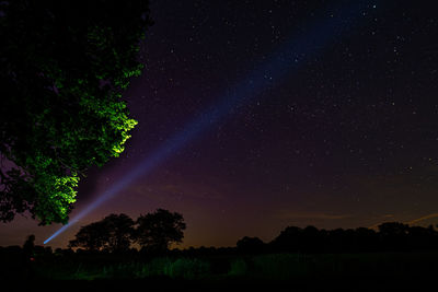 Scenic view of field against sky at night with flashlight beam