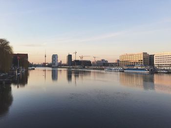 Scenic view of lake and city against sky at dusk