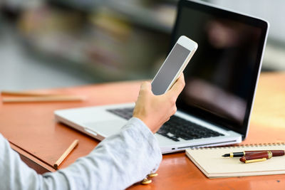 Midsection of man using smart phone on table