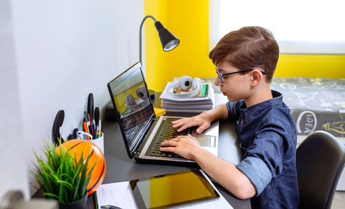 Boy wearing mask studying with laptop at home