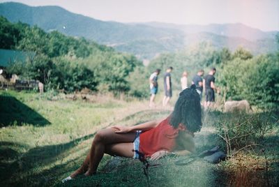Woman lying on grassy field against mountains