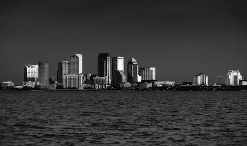 Sea by modern buildings against sky in city