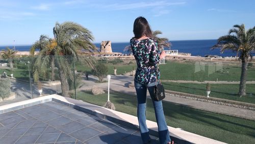 Rear view of woman standing against sea