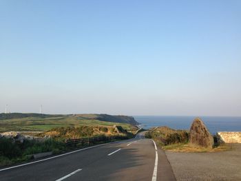 Road by sea against clear sky