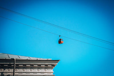 Low angle view of overhead cable cars against clear blue sky