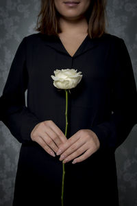 Midsection of woman holding flower while standing by plant
