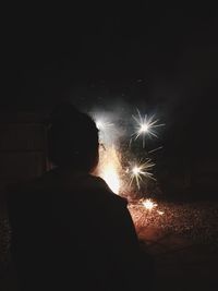 Rear view of man watching firework display at night