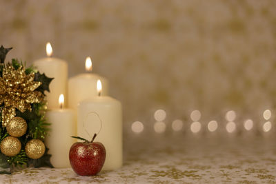 Close-up of christmas decorations by illuminated candles on table