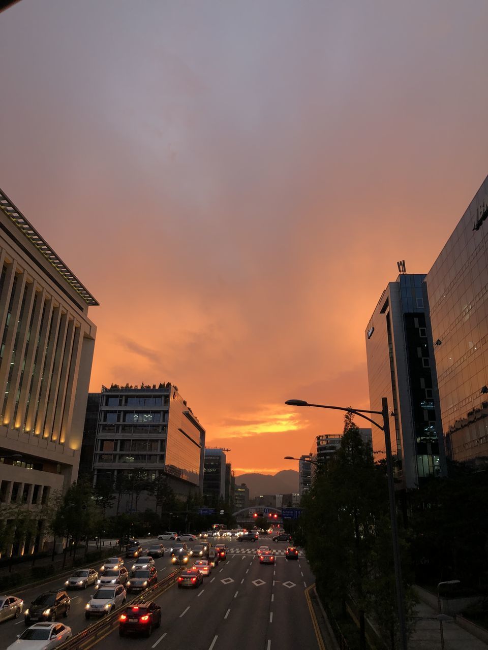 VIEW OF CITY STREET AND BUILDINGS AGAINST SKY DURING SUNSET