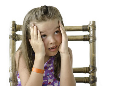 Close-up of girl sitting on chair against white background