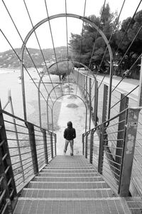 Rear view of man on railing against sky