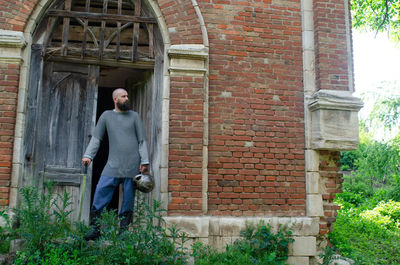 Viking warrior near old brick castle . sword and helmet. pensive look.old wooden door in torm 