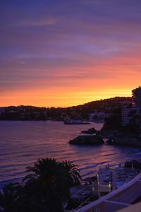 High angle view of sea and buildings against sky at sunset