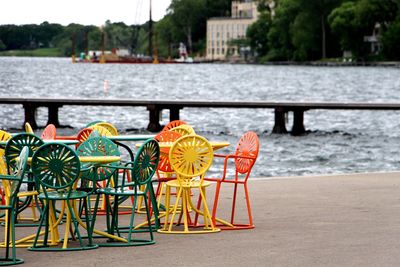 Multi colored chairs and table on port by river in city