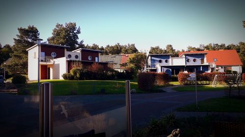 Houses by building against clear blue sky