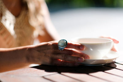 Close-up of female hands and coffee cup on table