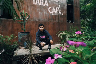 Full length of young man sitting on potted plant