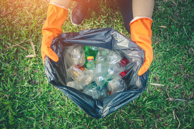 High angle view of person holding plastic bag on field